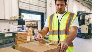 Warehouse worker pulling label off of a box